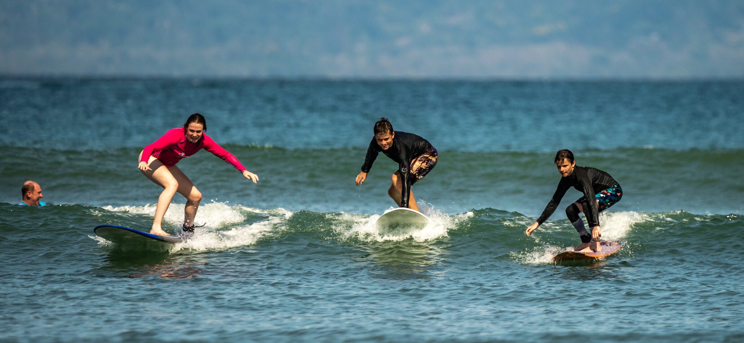 A surfer dropping into a clean turquoise wave at Playa Pan Dulce