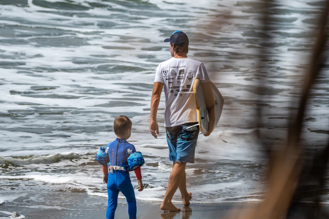Instructor walking a young grom out to the water