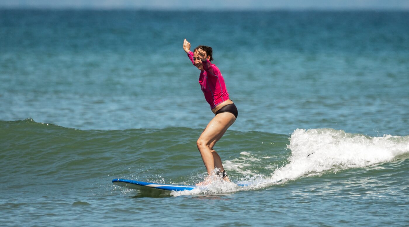 Student riding a wave with arms raised